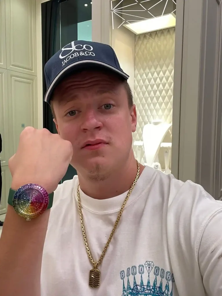 Mellstroy showing fist gesture in a white t-shirt and cap