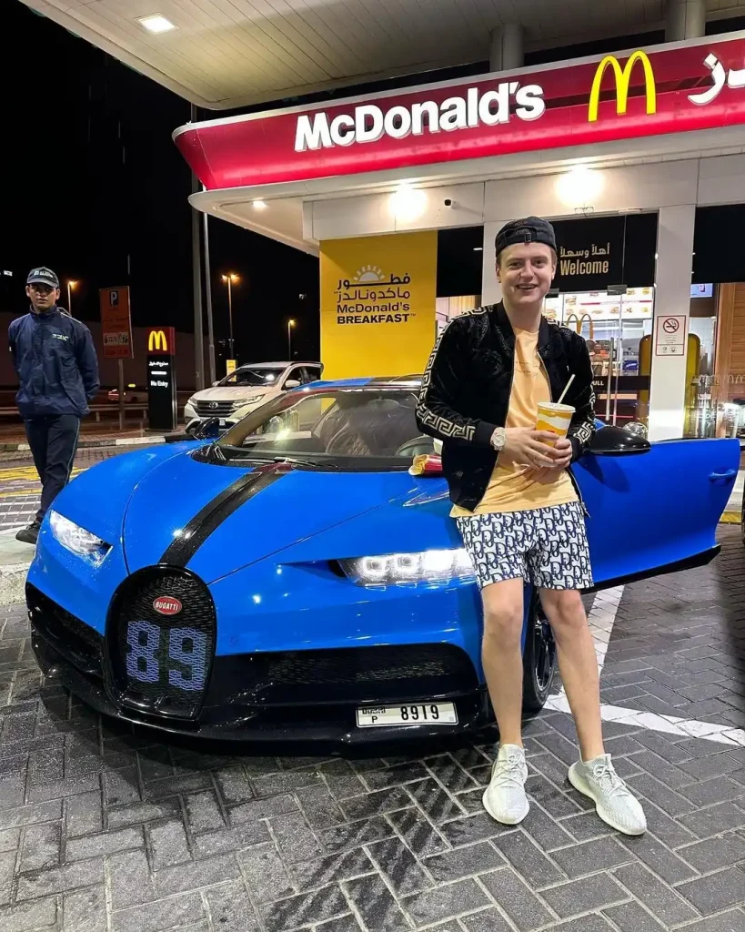 Mellstroy standing next to a blue sports car outside a showroom